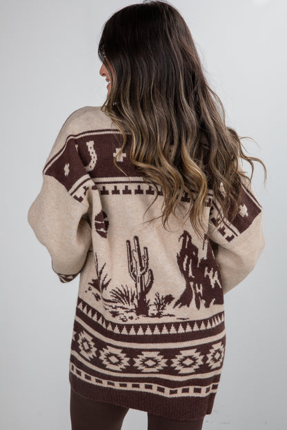 Person wearing a patterned sweater with desert-themed design on a plain background