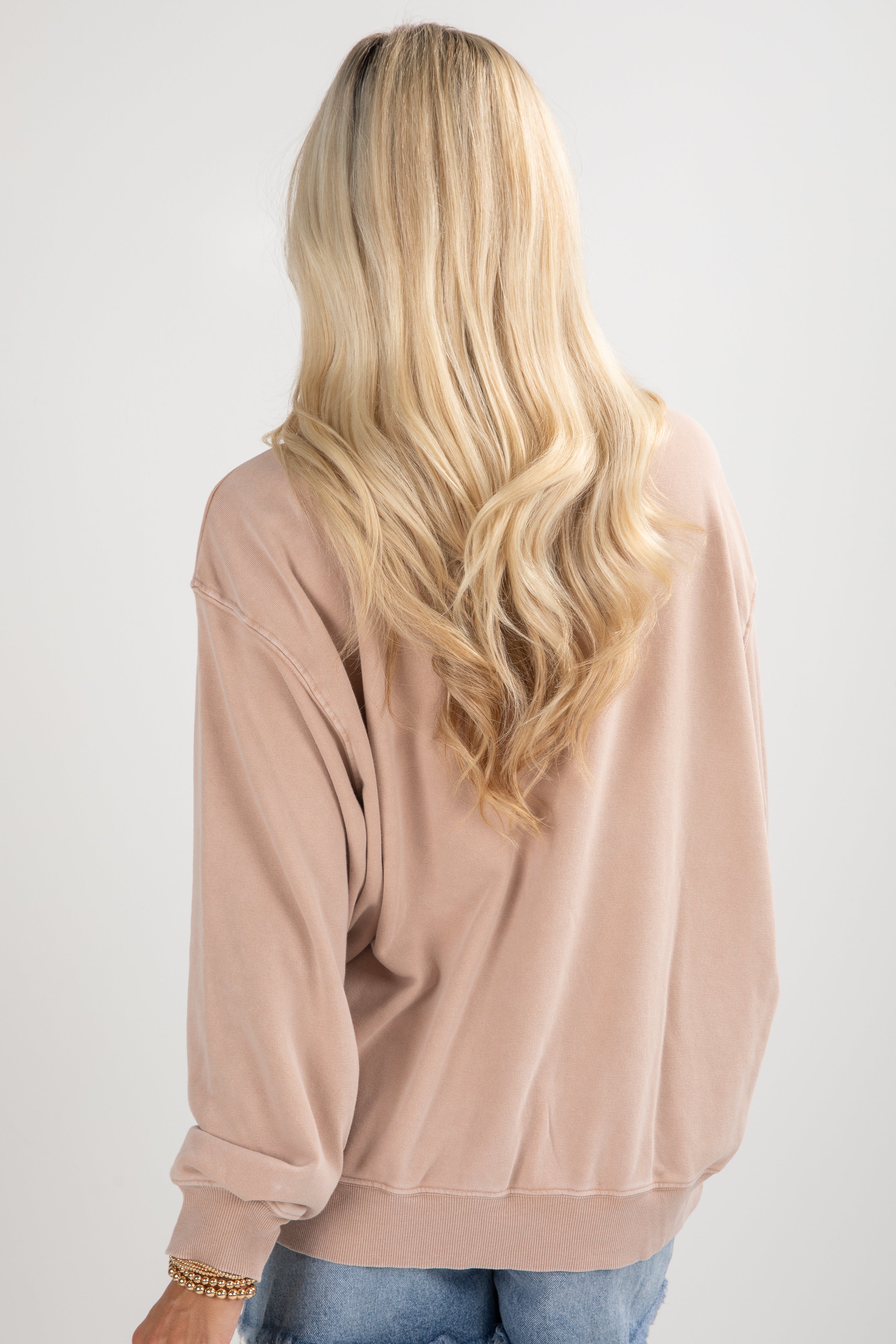 Person wearing a beige oversized sweater on a plain background