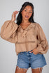 Woman wearing a beige blouse with puffed sleeves and denim shorts on a plain background