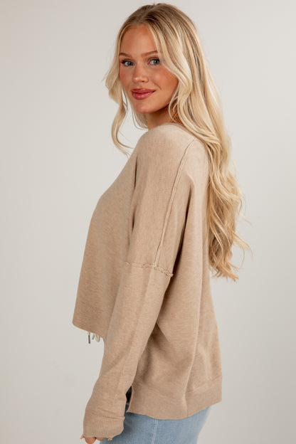 Woman wearing a beige sweater against a plain background