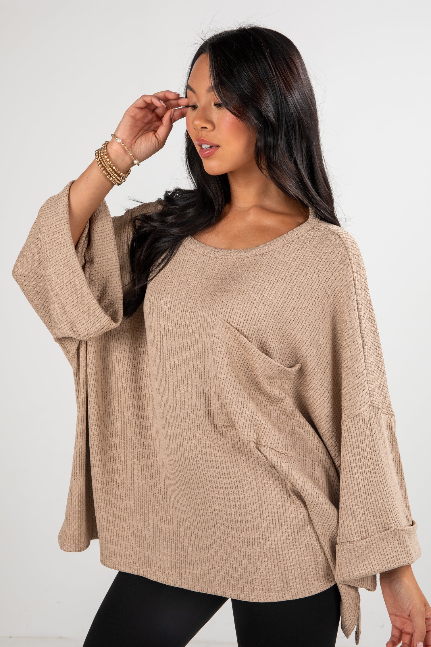 Woman wearing a beige sweater with a plain background