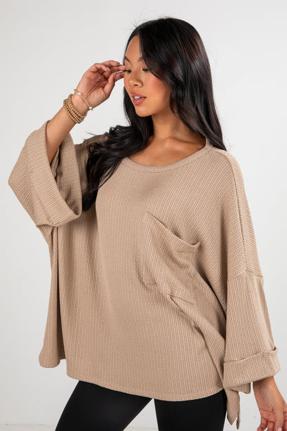 Woman wearing a beige sweater with a plain background