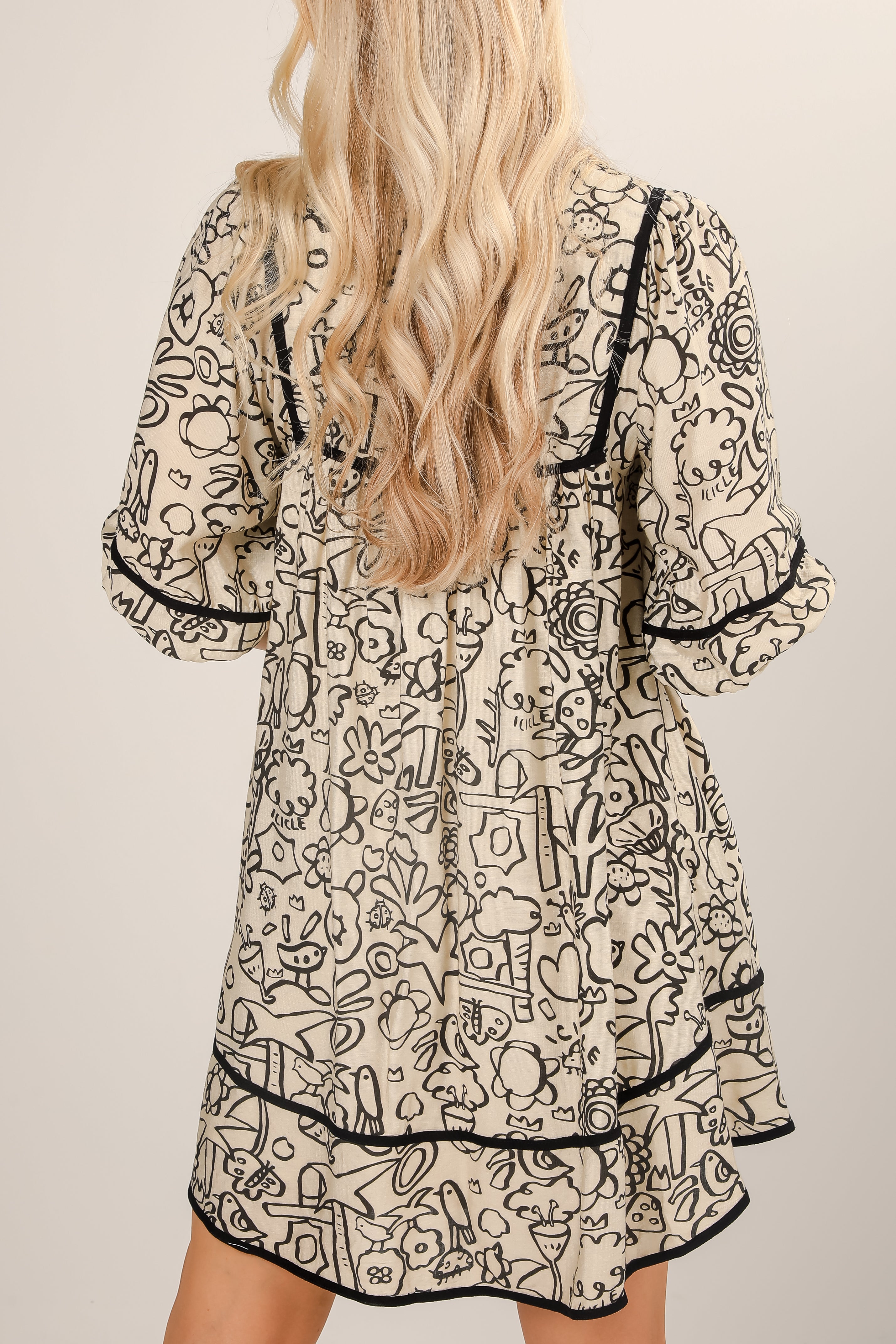 Woman wearing a patterned dress with black trim on a beige background