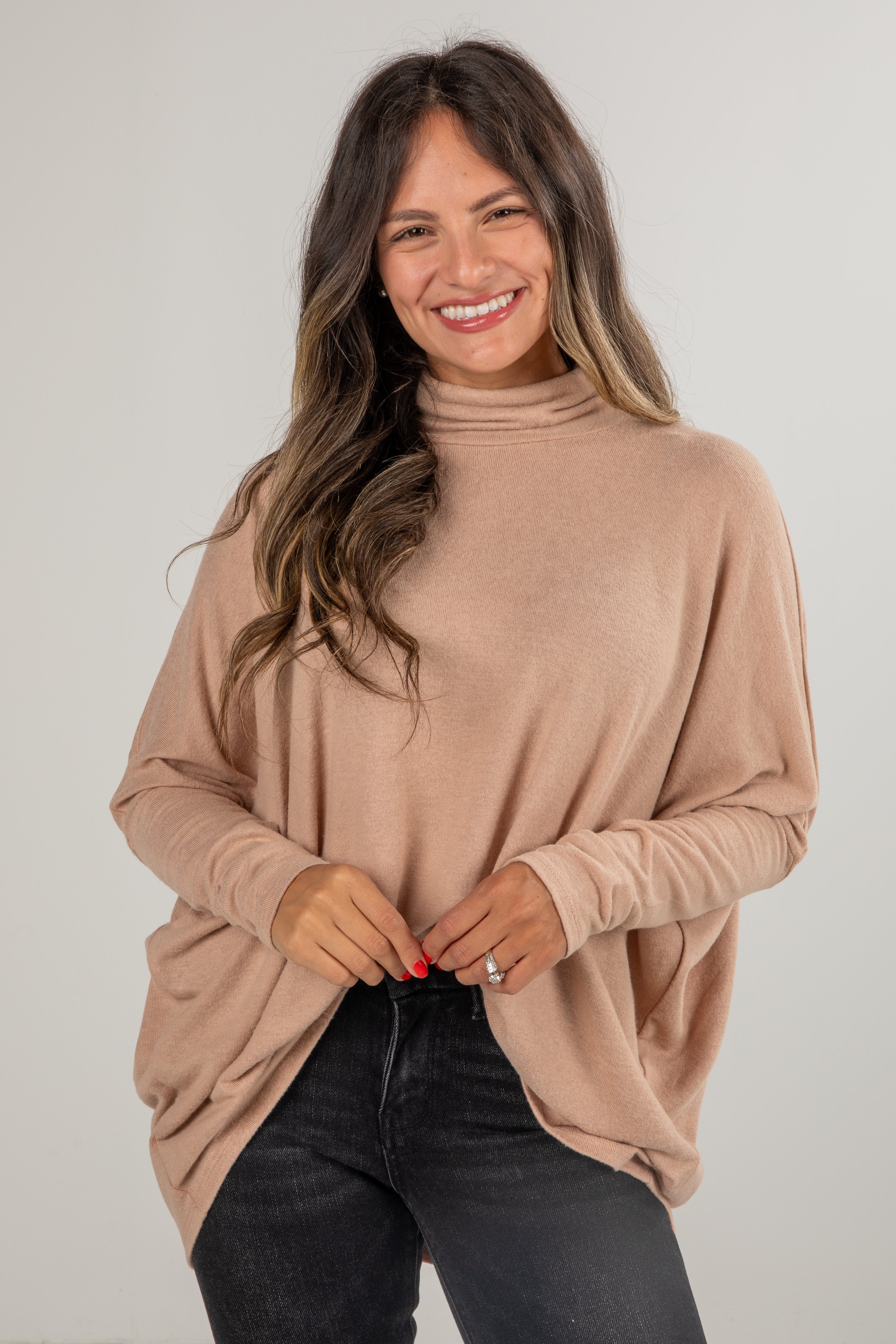 Woman wearing a beige turtleneck sweater against a plain background