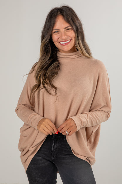 Woman wearing a beige turtleneck sweater against a plain background
