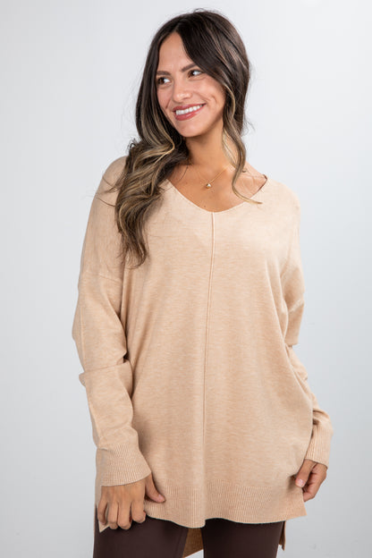 Woman wearing a beige sweater against a plain background
