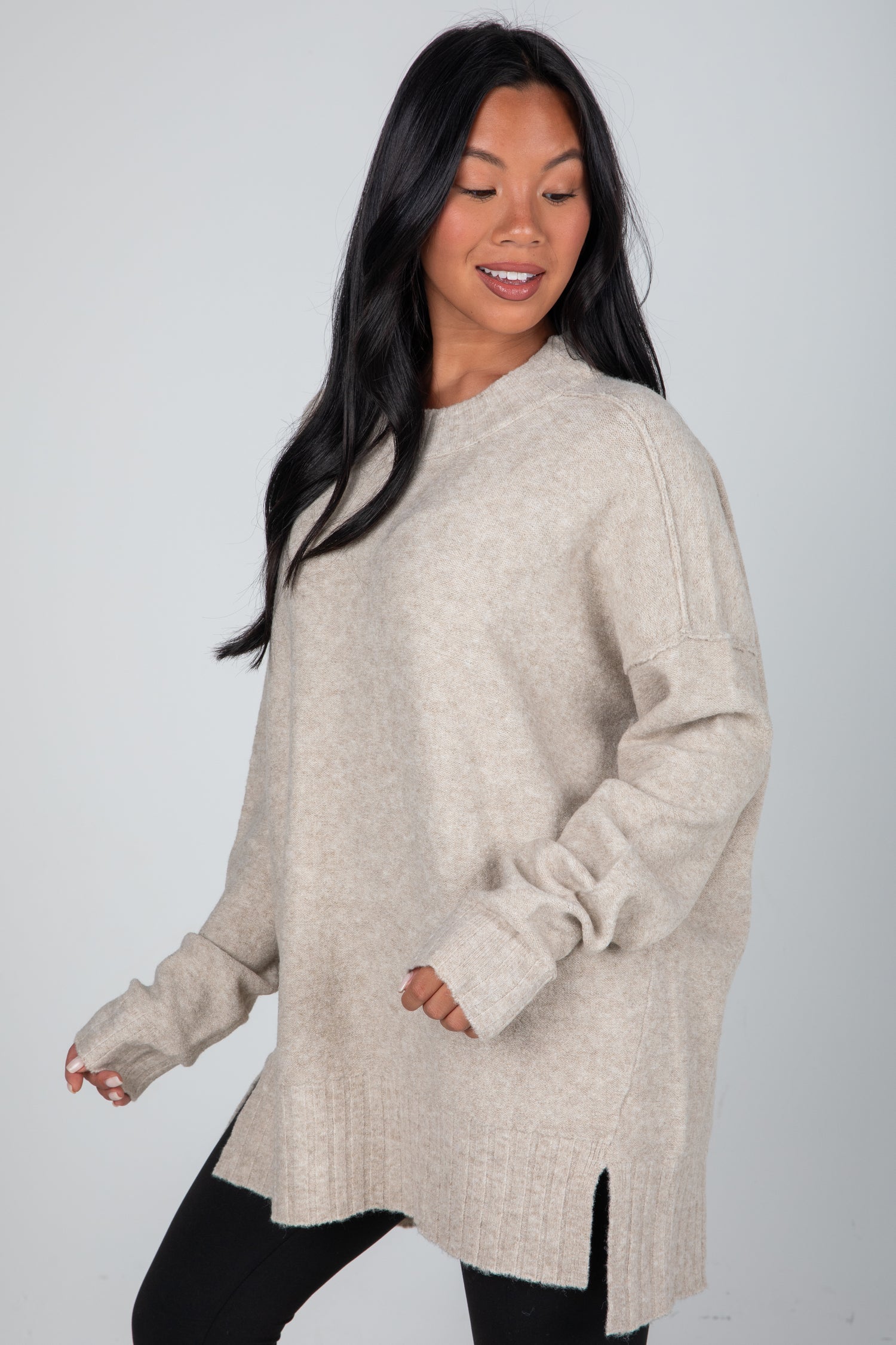 Woman wearing a beige sweater against a plain background