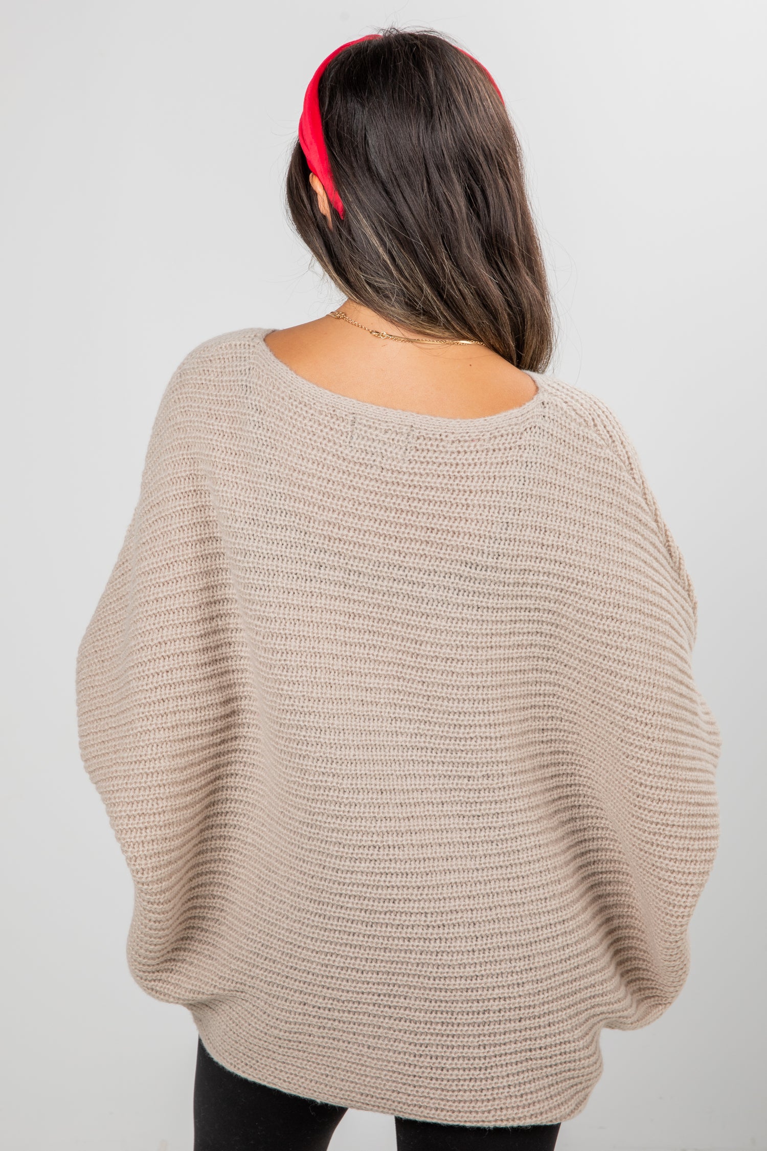 Person wearing a beige sweater with a plain background