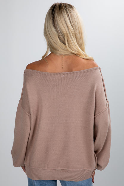 Person wearing a brown off-shoulder sweater on a plain background