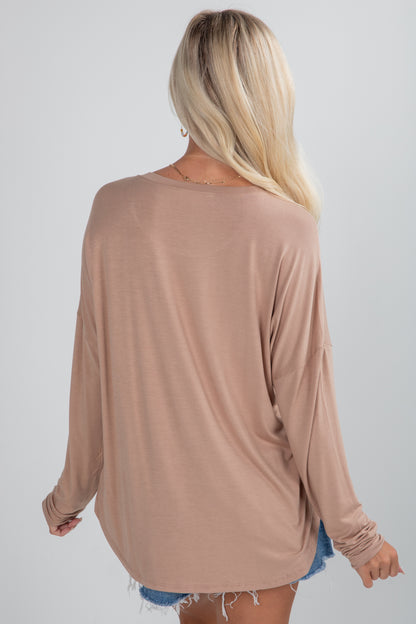 Woman wearing a beige long-sleeve top on a plain background