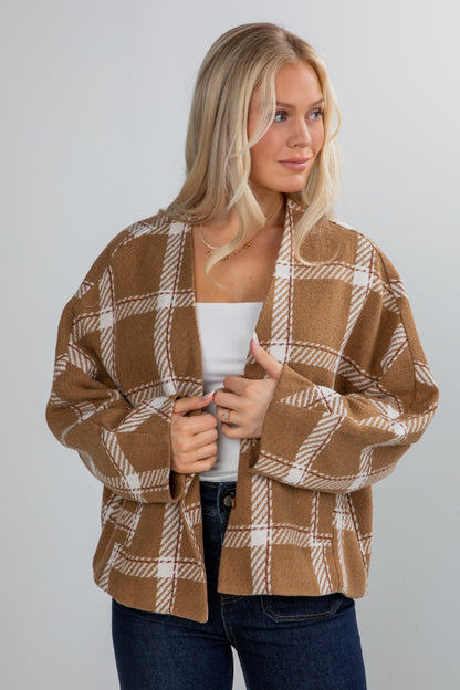 Woman wearing a brown and beige plaid cardigan on a plain background