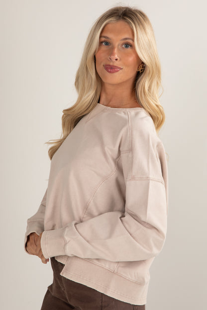 Woman wearing a beige sweater against a plain background