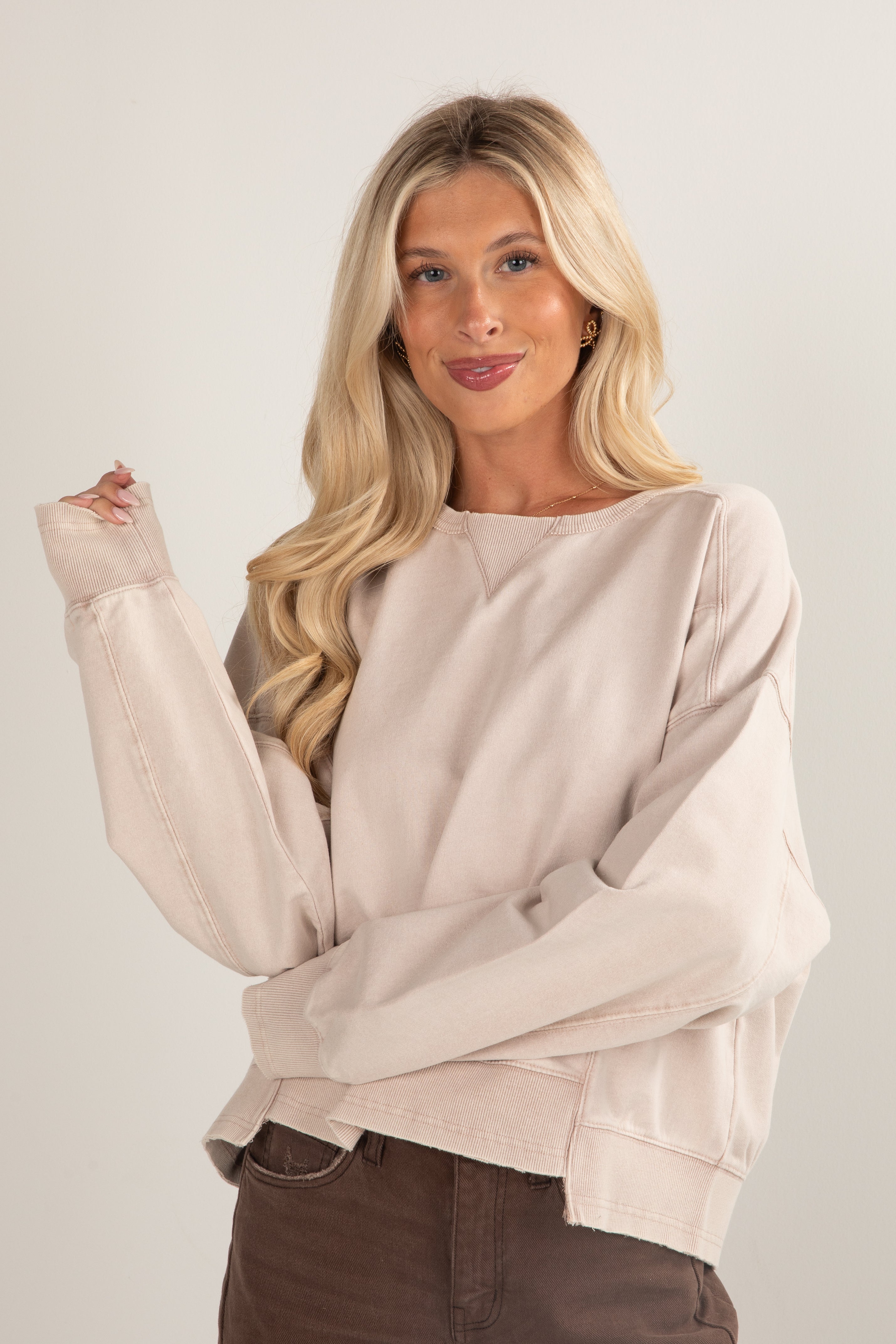 Woman wearing a beige sweater against a plain background