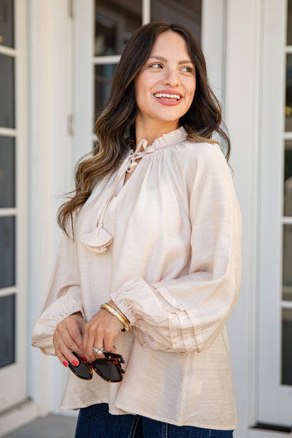 Woman wearing a beige blouse standing outside a building
