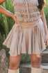 Person wearing a layered ruffled top and beige skirt with boots, standing outdoors.