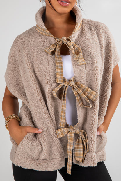 Beige fleece vest with plaid tie details worn by a person on a white background