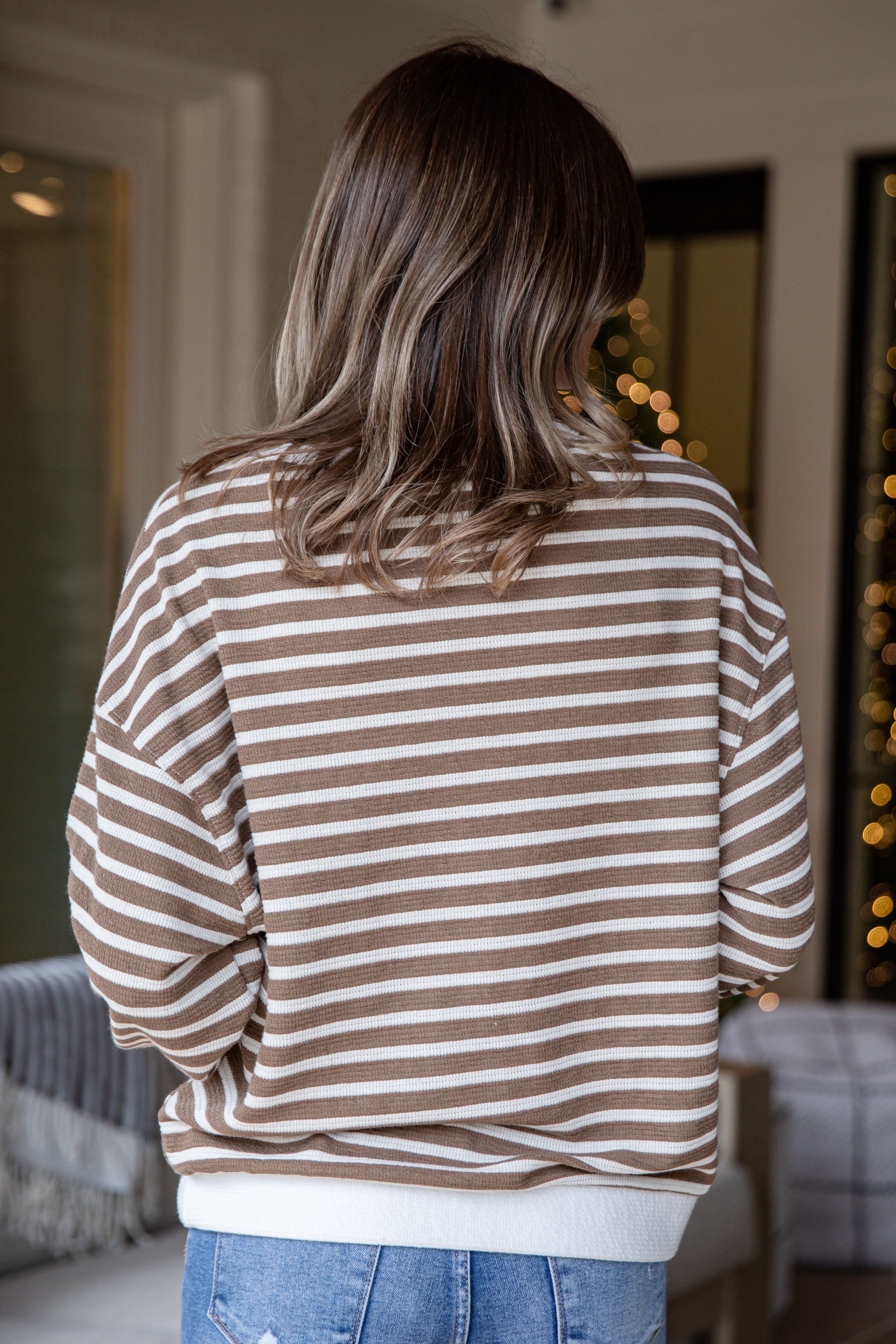Person wearing a brown and white striped sweater in an indoor setting