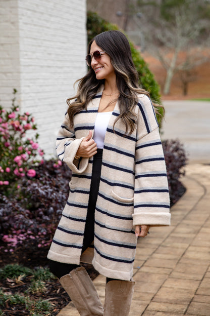 Woman wearing a long, striped coat with a white background