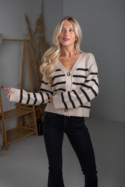 Woman wearing a striped sweater and black pants in a neutral setting