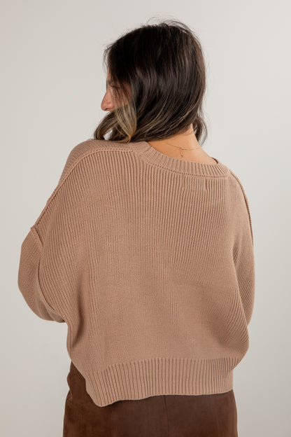 Woman wearing a brown sweater against a plain background