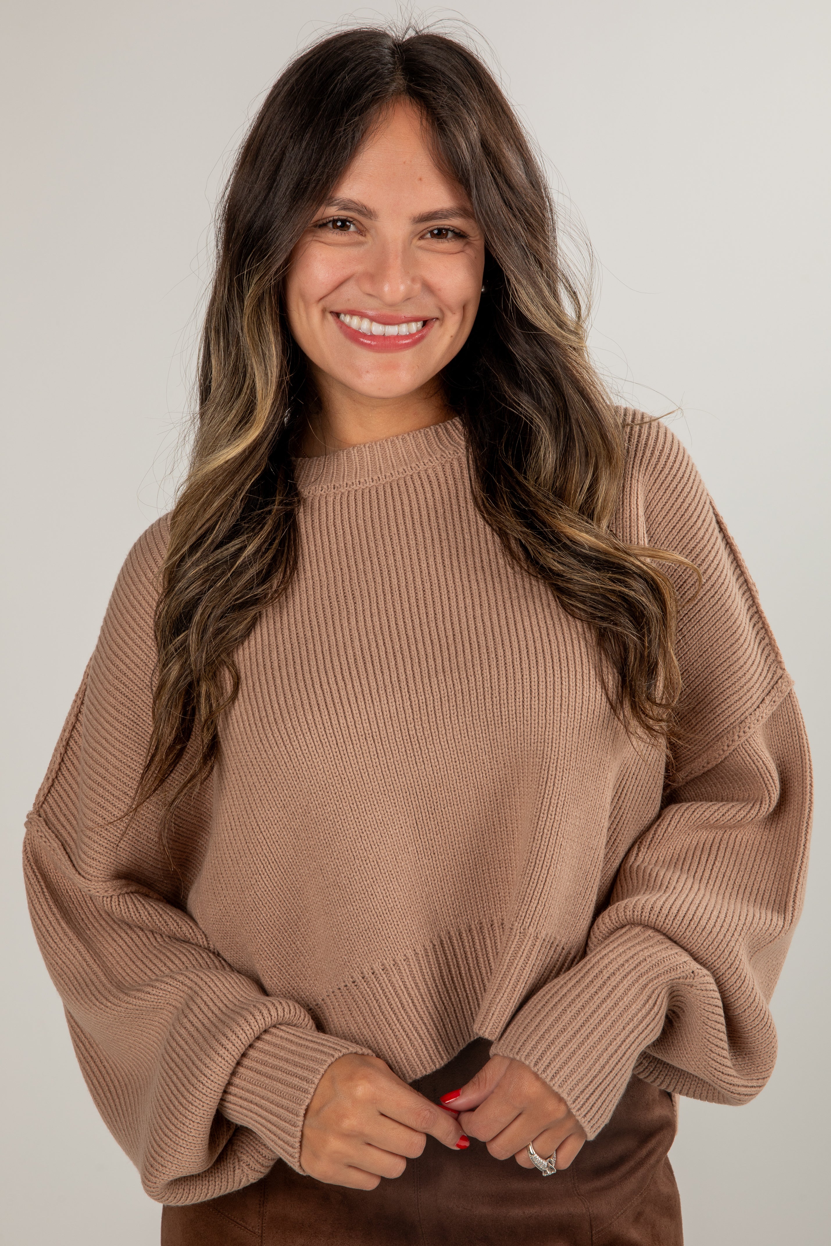 Woman wearing a beige sweater against a plain background