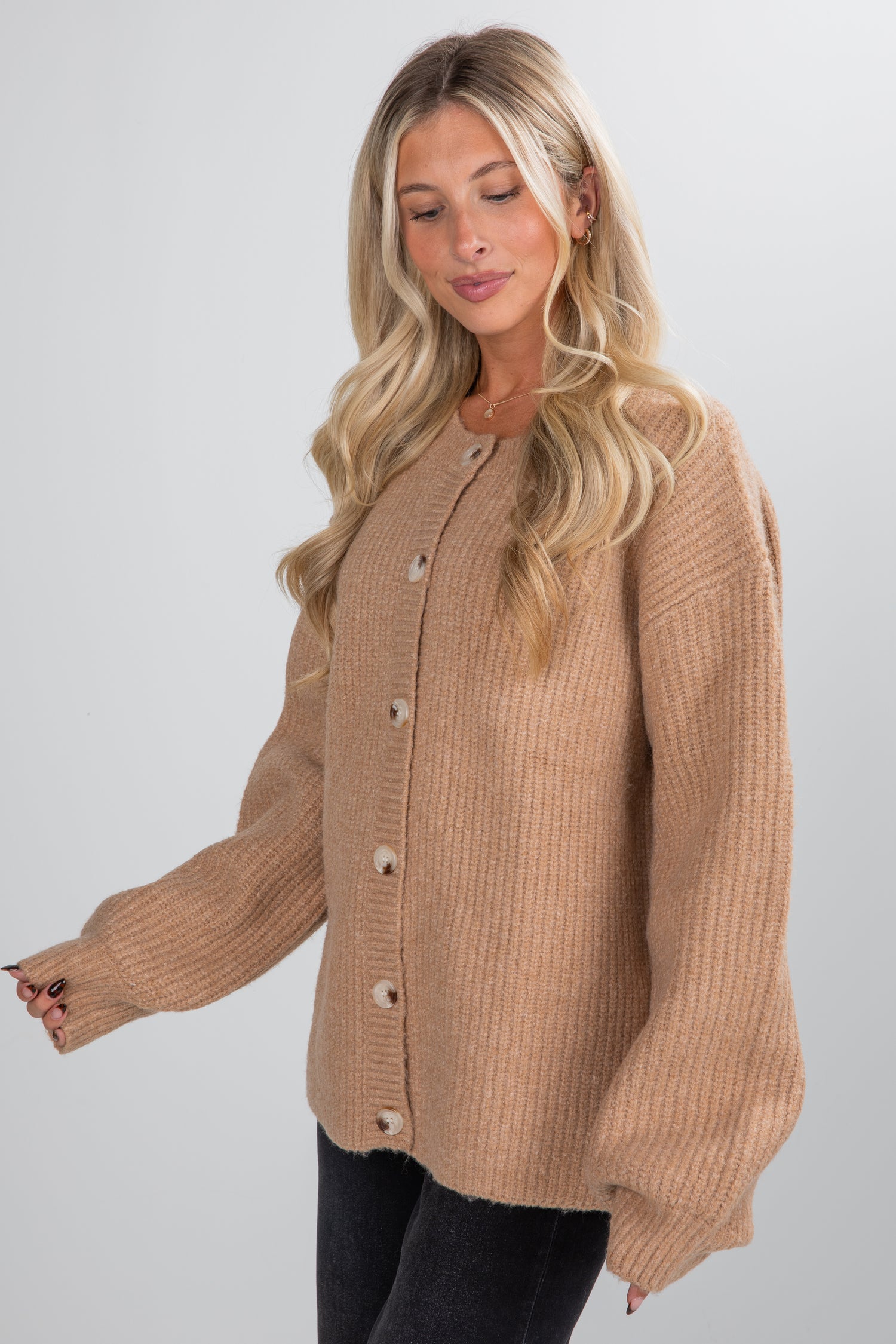 Woman wearing a beige cardigan against a white background