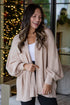 Woman wearing a beige cardigan in a cozy living room with Christmas decorations.