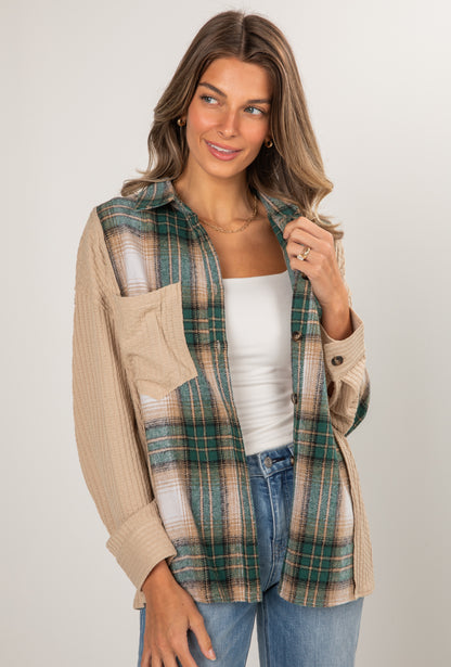 Woman wearing a plaid shirt over a beige cardigan on a plain background