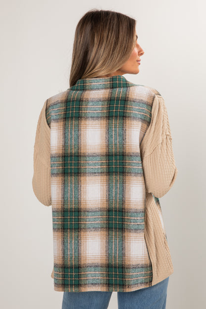 Woman wearing a plaid vest over a beige sweater on a plain background