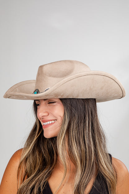 Woman wearing a beige cowboy hat against a plain background