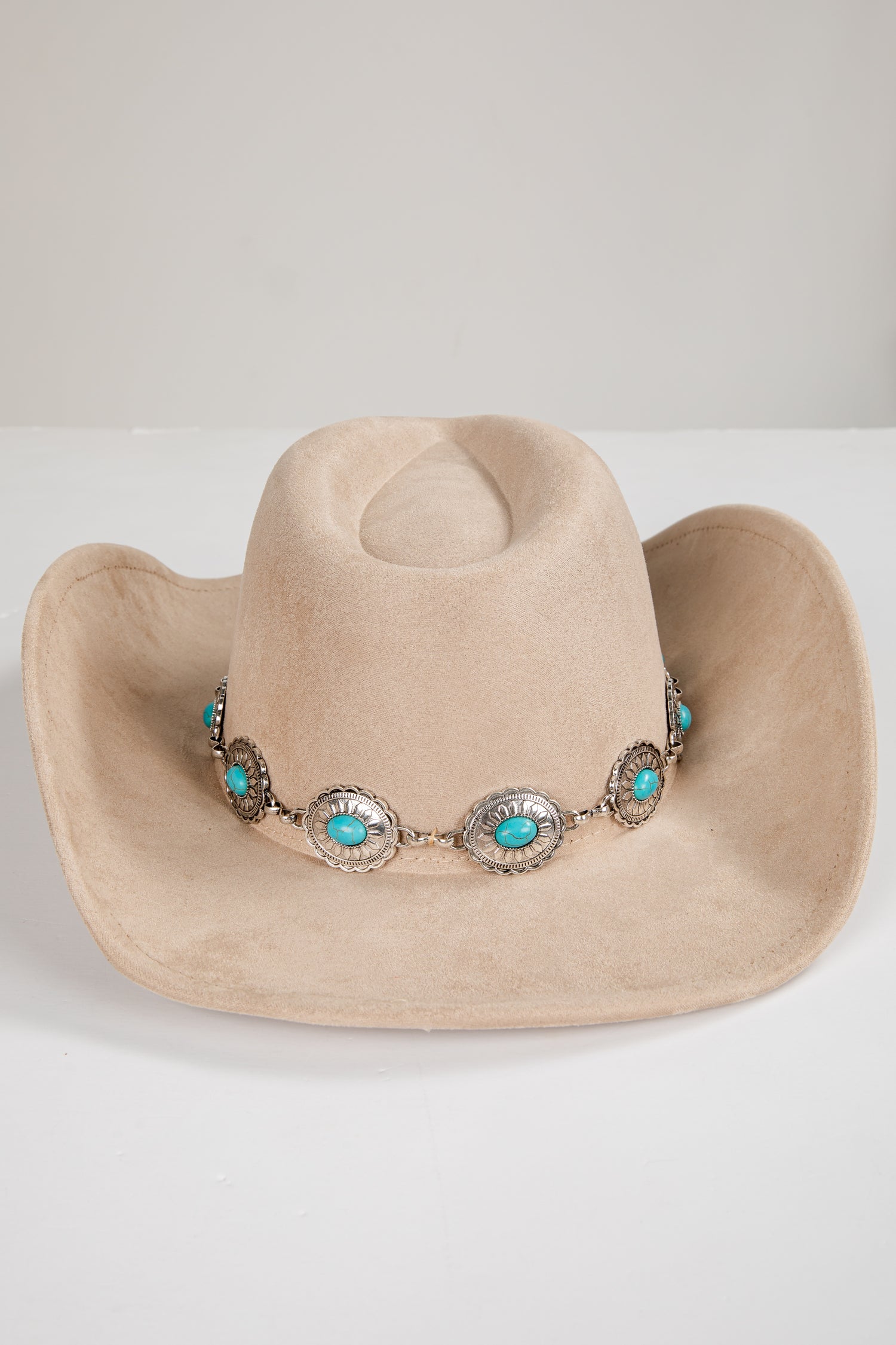 Beige cowboy hat with turquoise and silver embellishments on a white background