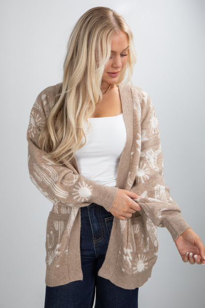Woman wearing a beige cardigan with a white pattern on a plain background