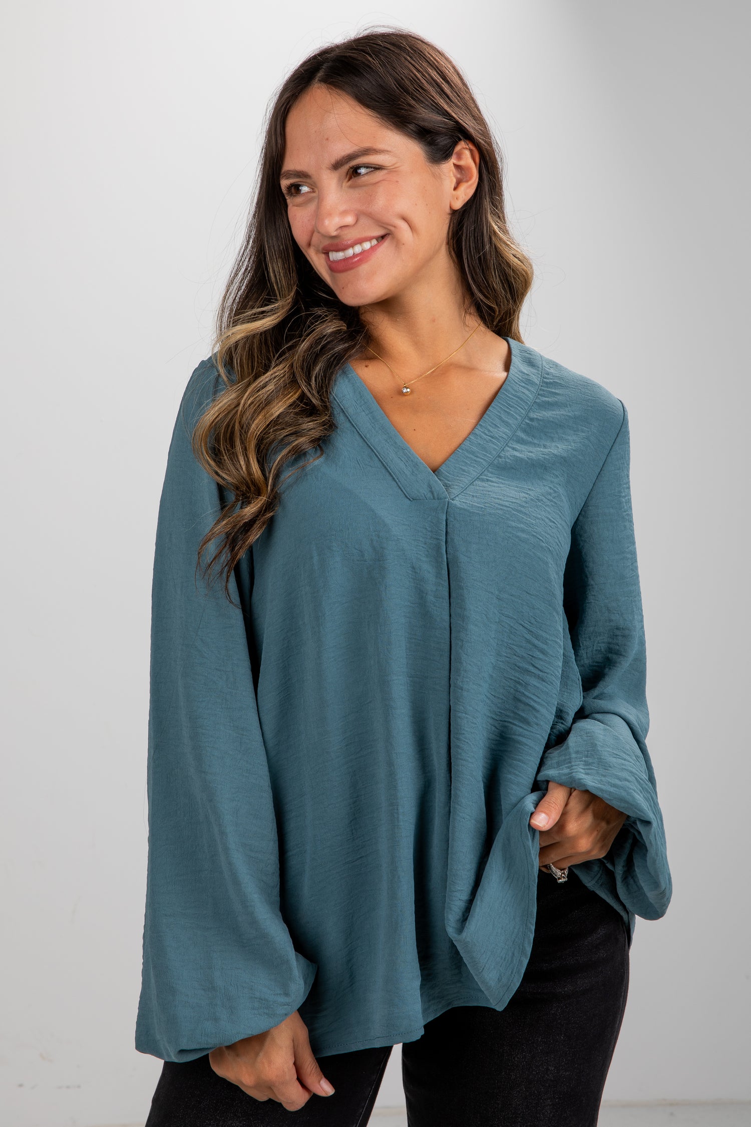 Woman wearing a teal sweater against a plain background