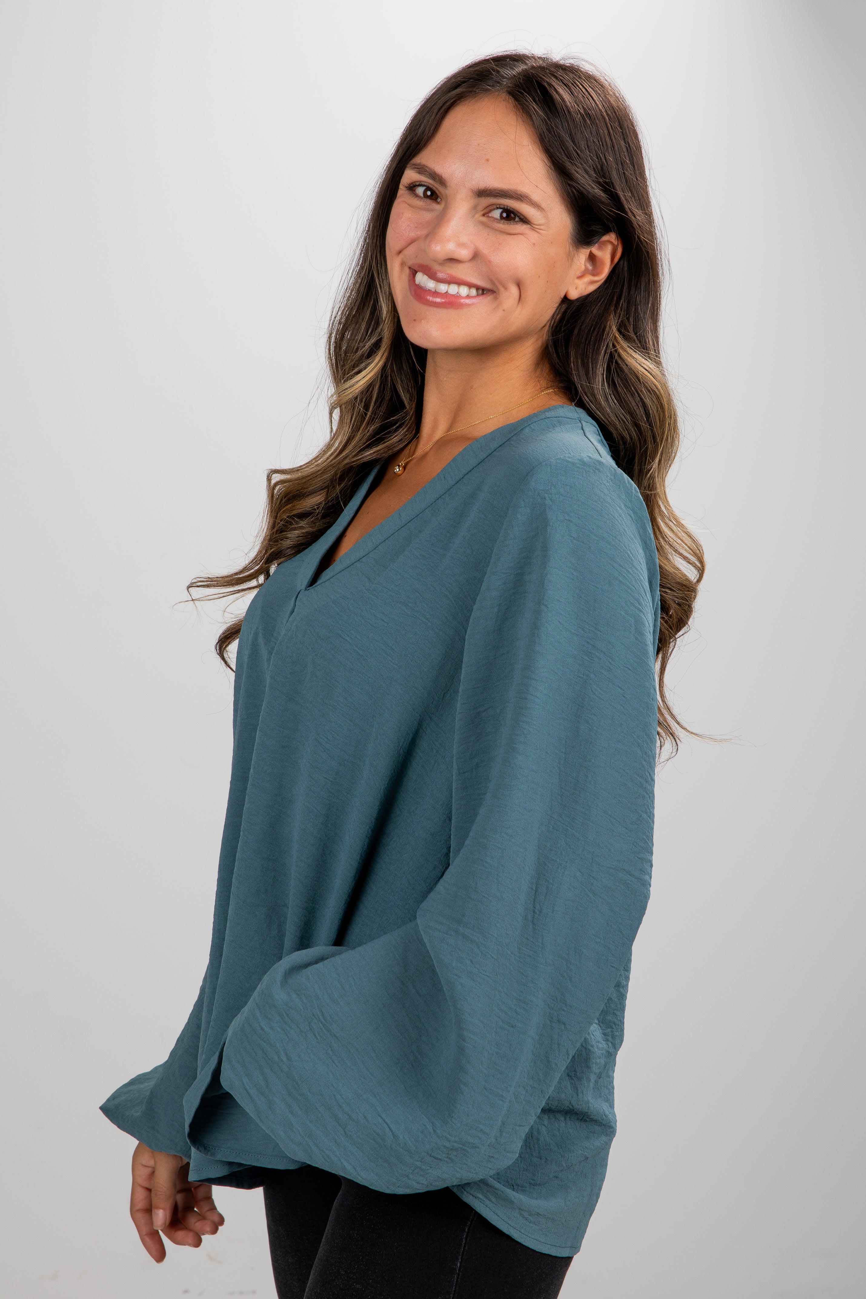Woman wearing a teal sweater against a plain background