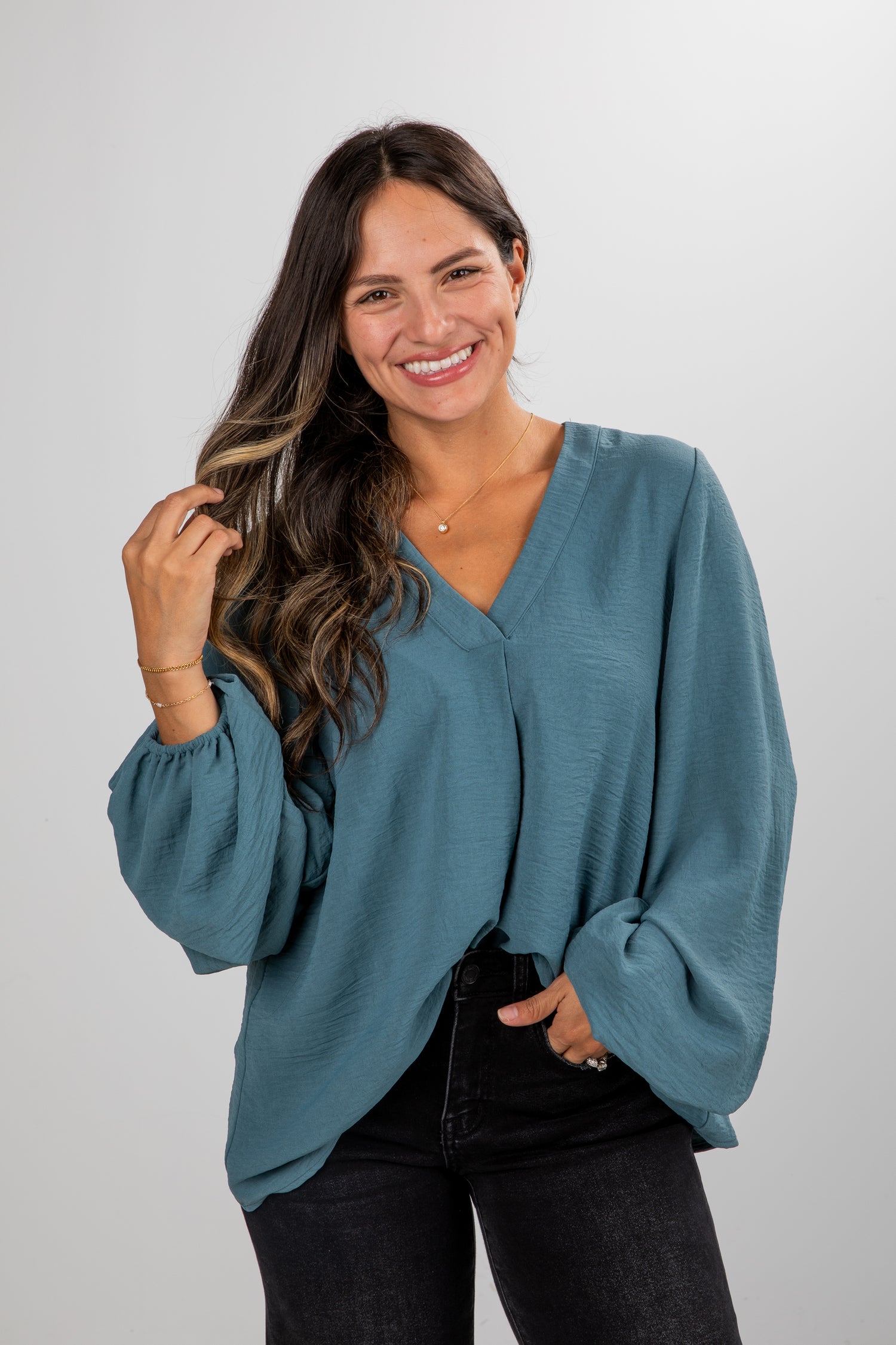 Woman wearing a teal blouse with a plain background