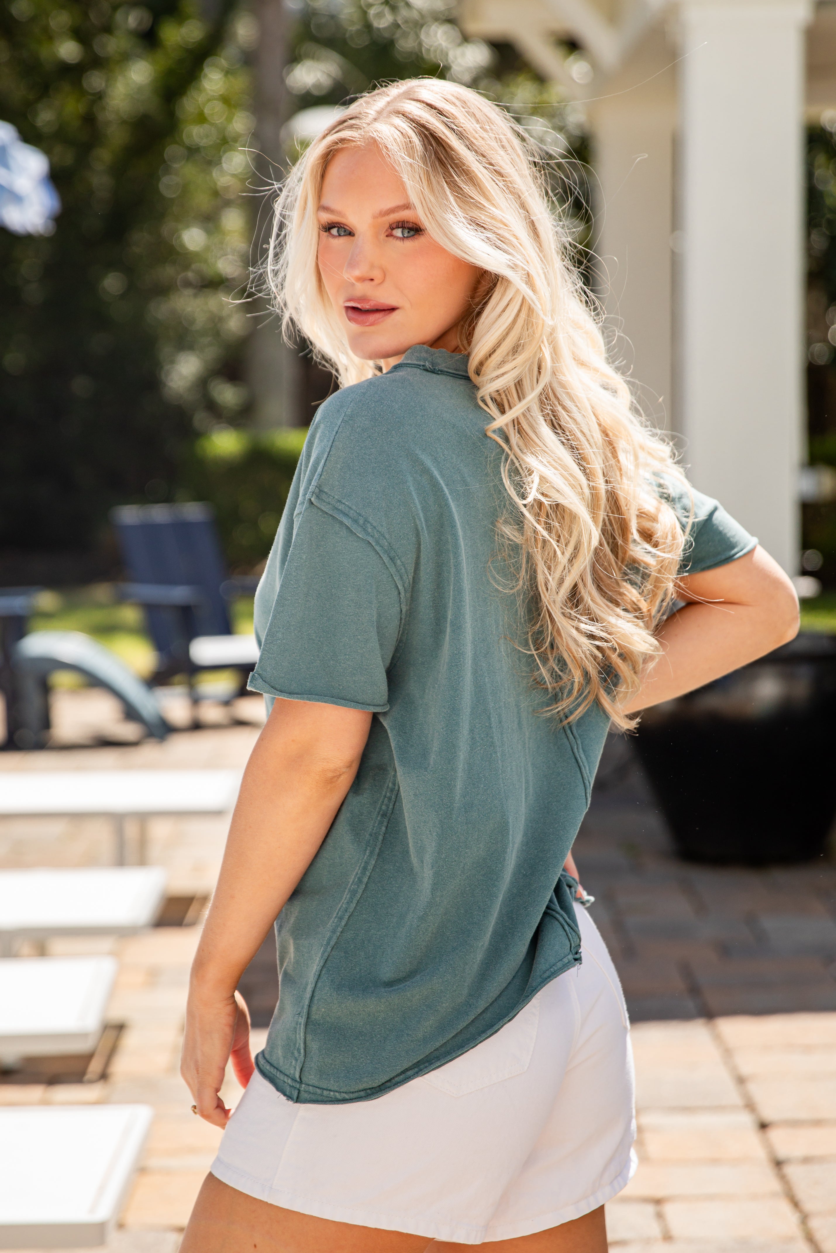 Woman wearing a green shirt and white shorts outdoors