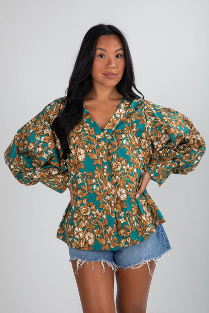 Woman wearing a floral blouse with puffed sleeves on a white background