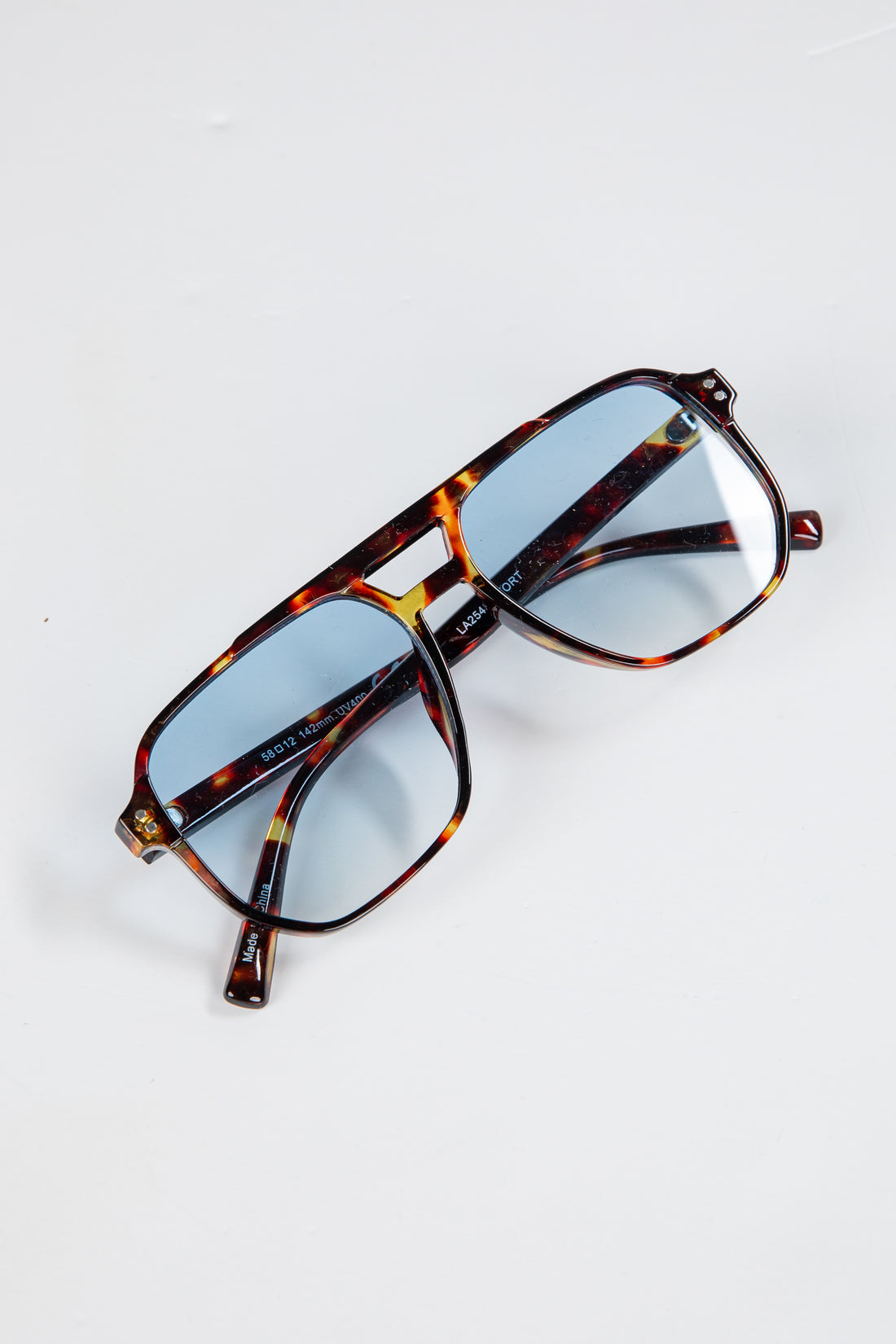 Tortoiseshell sunglasses with blue lenses on a white background