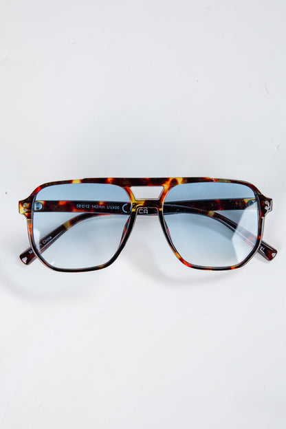 Tortoiseshell sunglasses with blue lenses on a white background
