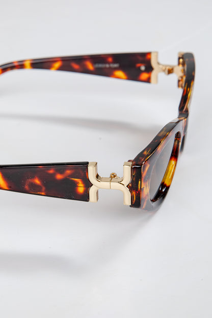 Tortoiseshell sunglasses with gold accents on a white background