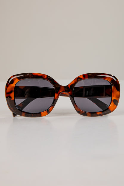 Sunglasses with tortoiseshell frame and dark lenses on a light gray background