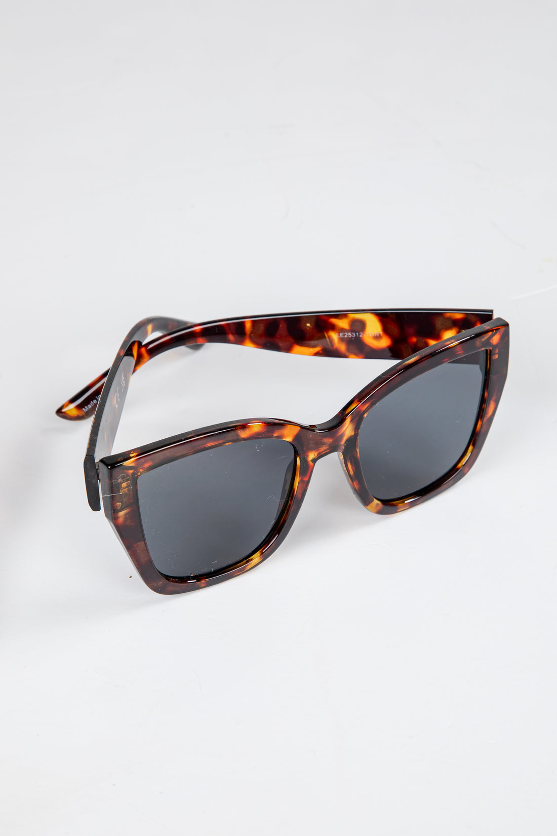 Tortoiseshell sunglasses with dark lenses on a white background