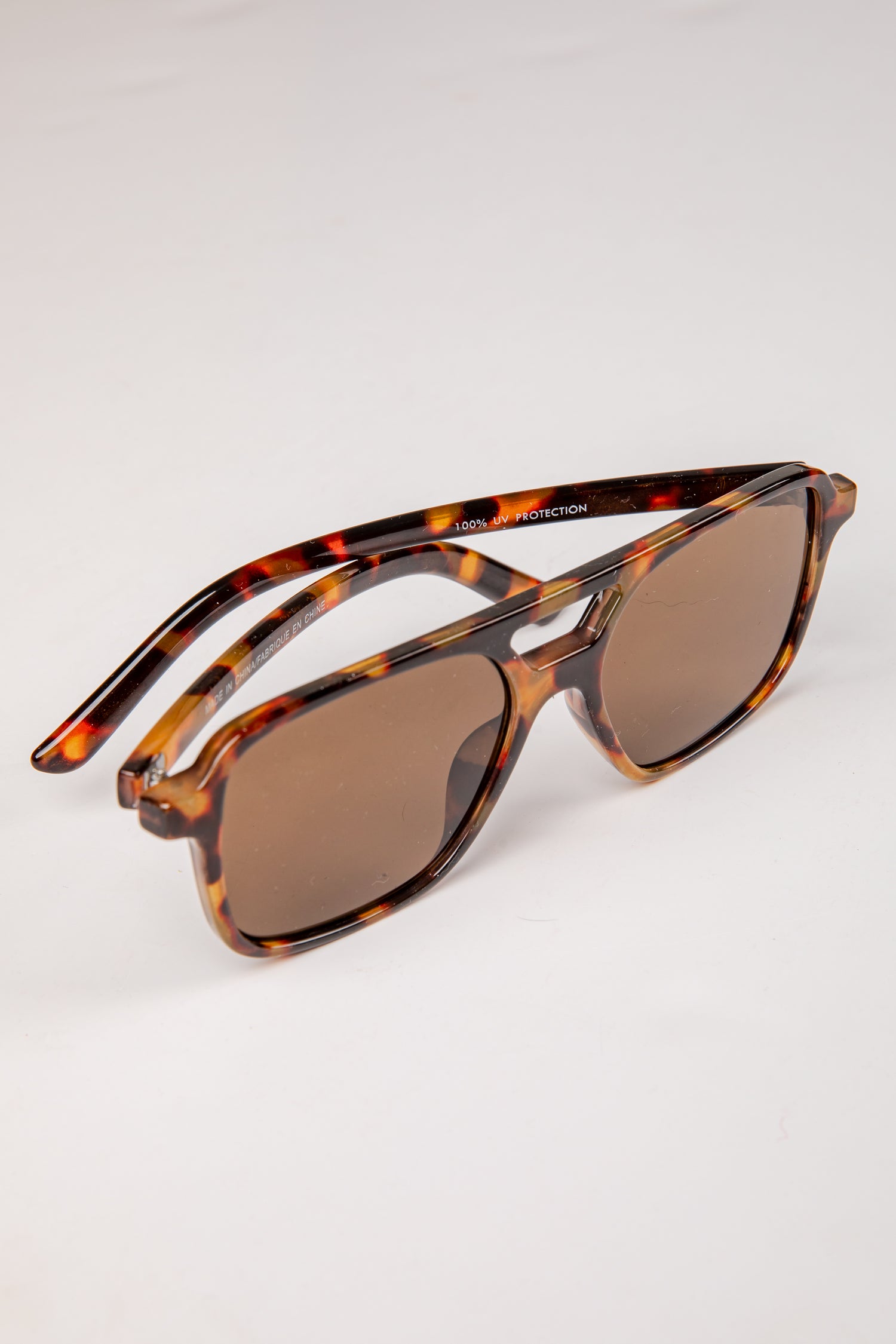 Sunglasses with tortoiseshell frame and brown lenses on a white background