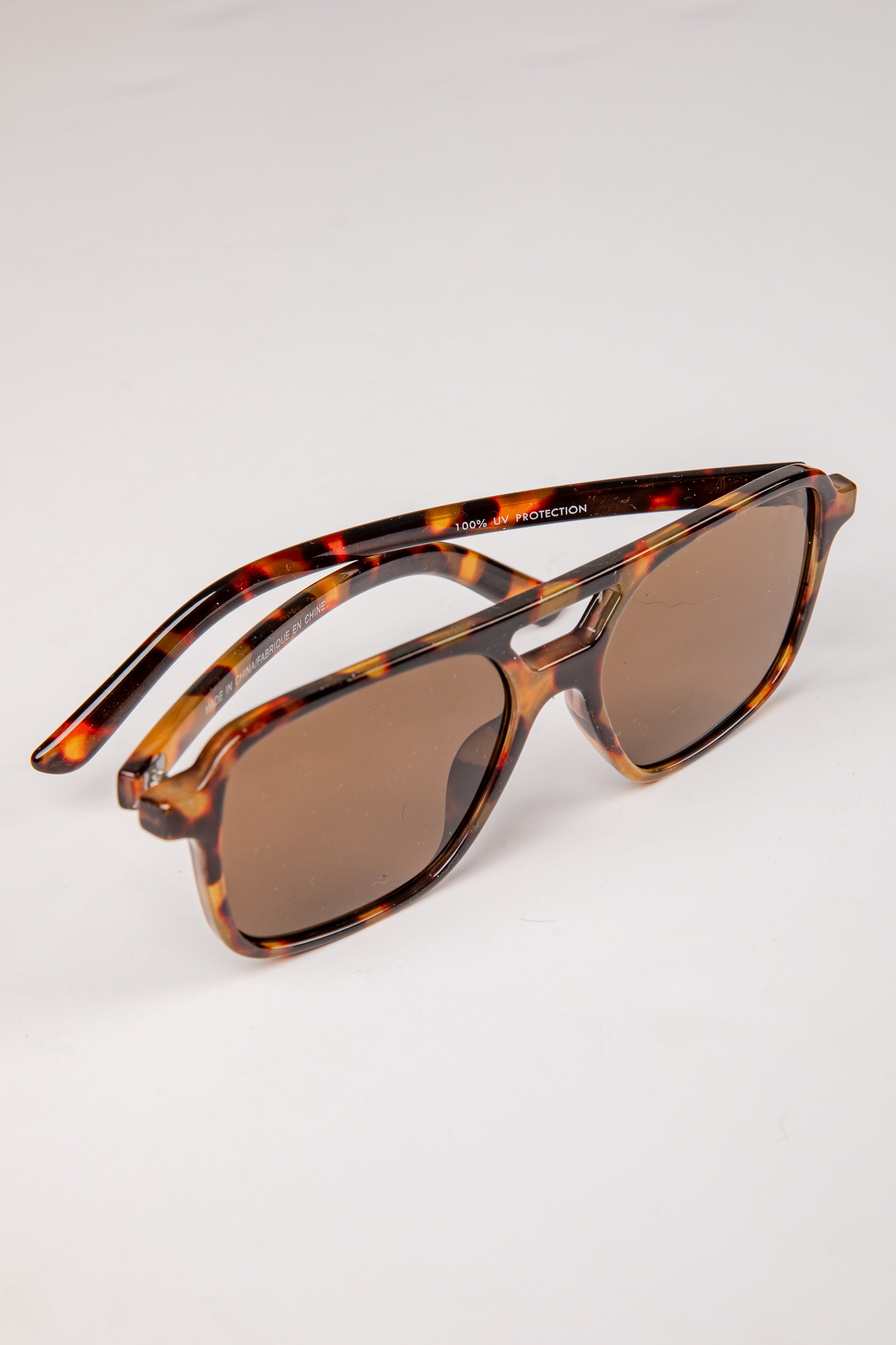 Sunglasses with tortoiseshell frame and brown lenses on a white background