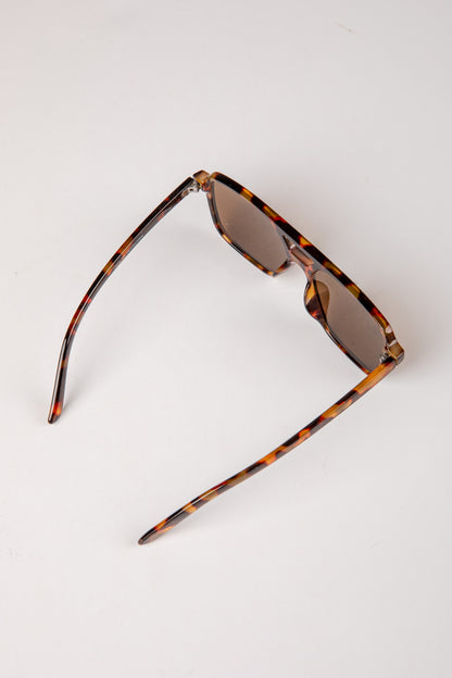 Sunglasses with tortoiseshell frame and dark lenses on a white background
