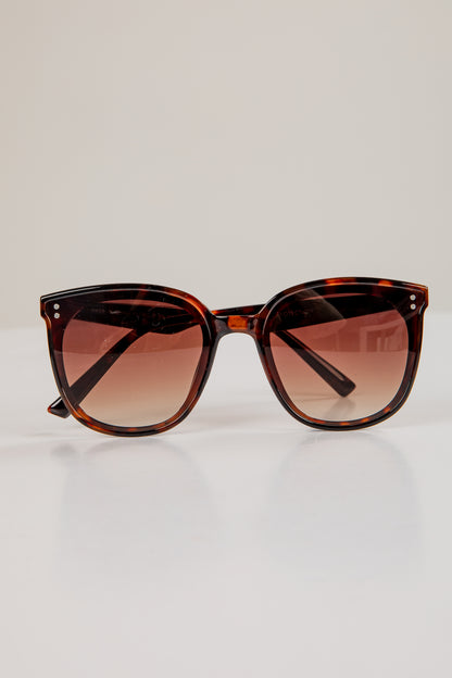 Tortoiseshell sunglasses with brown gradient lenses on a light gray background