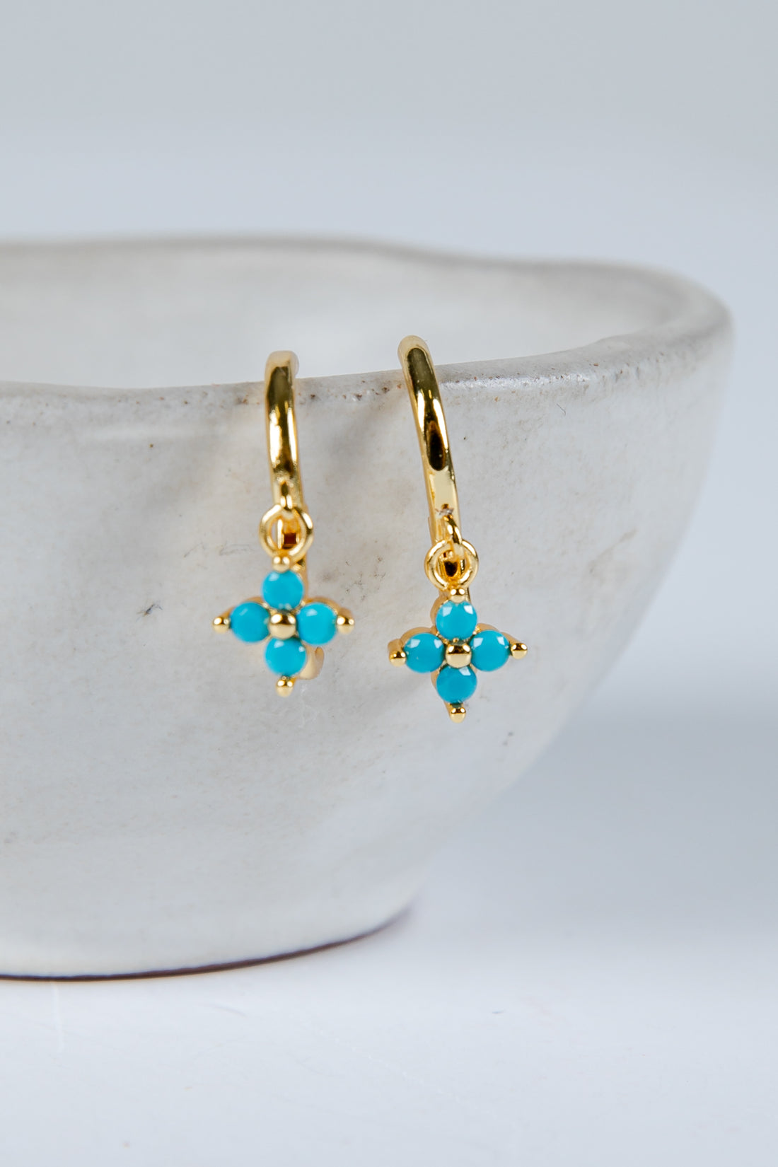 Gold earrings with turquoise stones on a white background