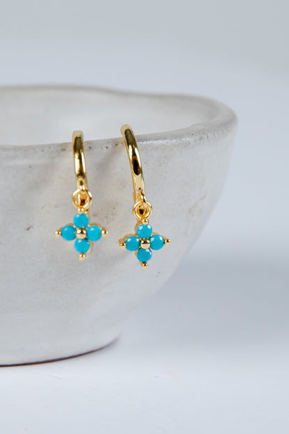 Gold earrings with turquoise stones on a white background