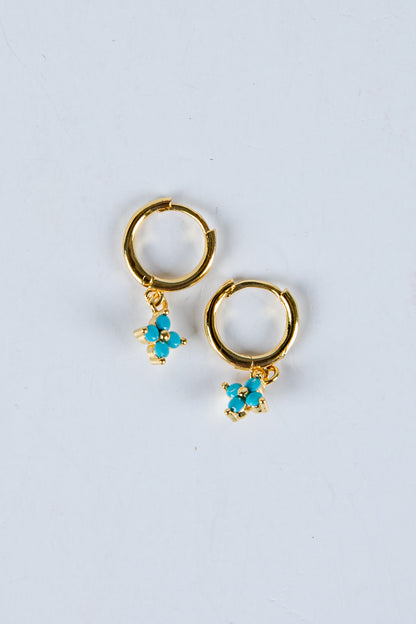 Gold hoop earrings with turquoise flower charms on a light gray background