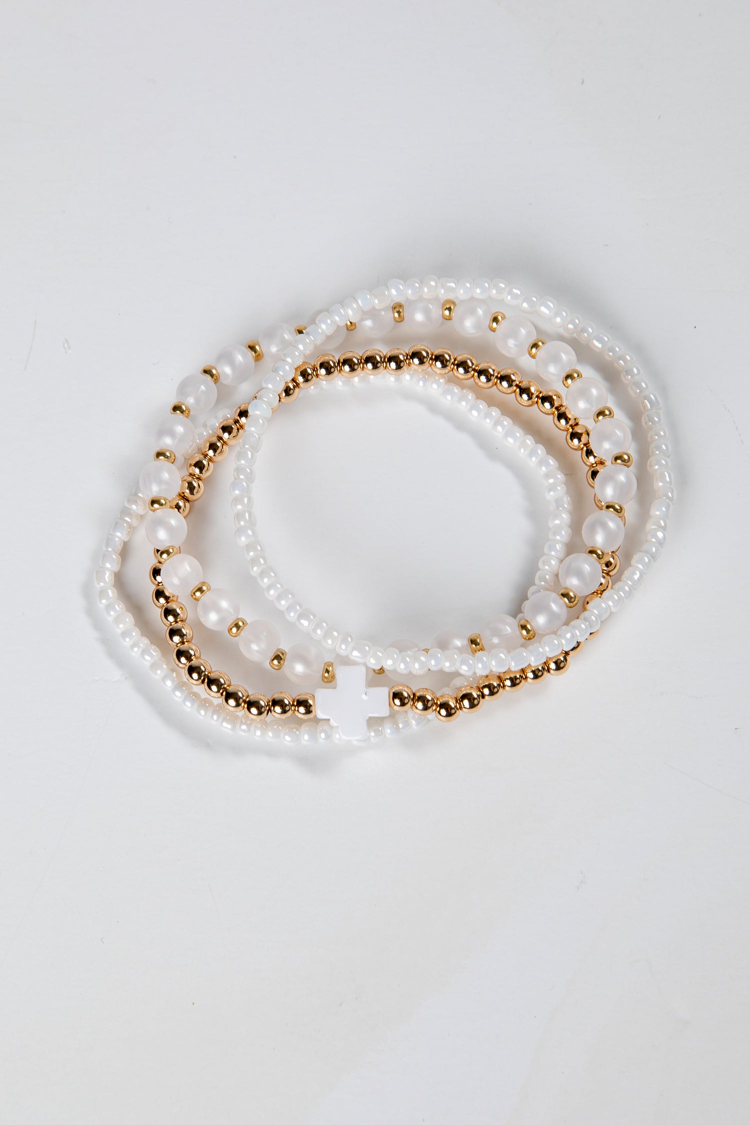 Set of pearl and gold beaded bracelets on a light gray background